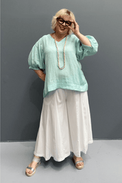 'Holly' linen top for plus size women features a high-low hem, balloon sleeves, and a comfortable fit for warm weather.