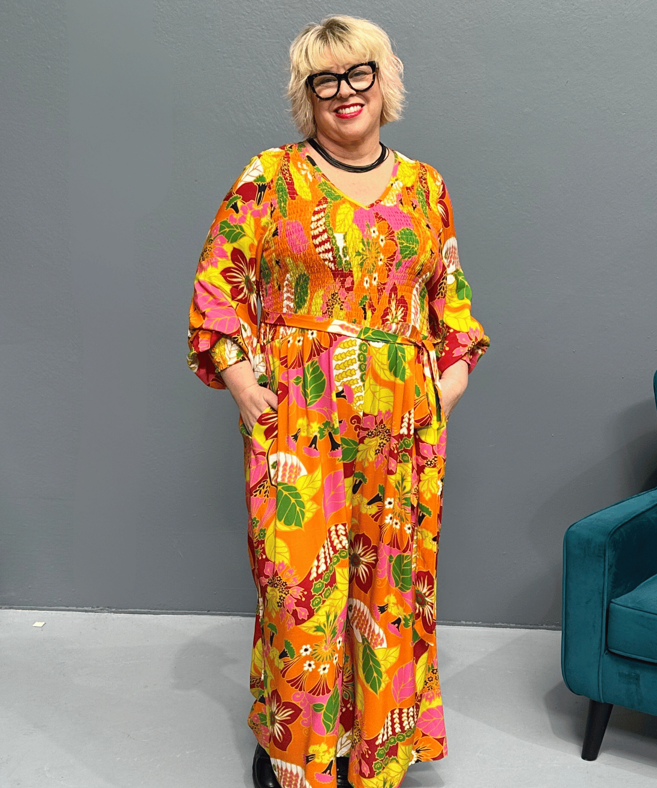 Plus-size 'FEARLESS' jumpsuit in retro print with pink, orange, and golden yellows, featuring a relaxed wide-leg cut and flattering shirred bodice.
