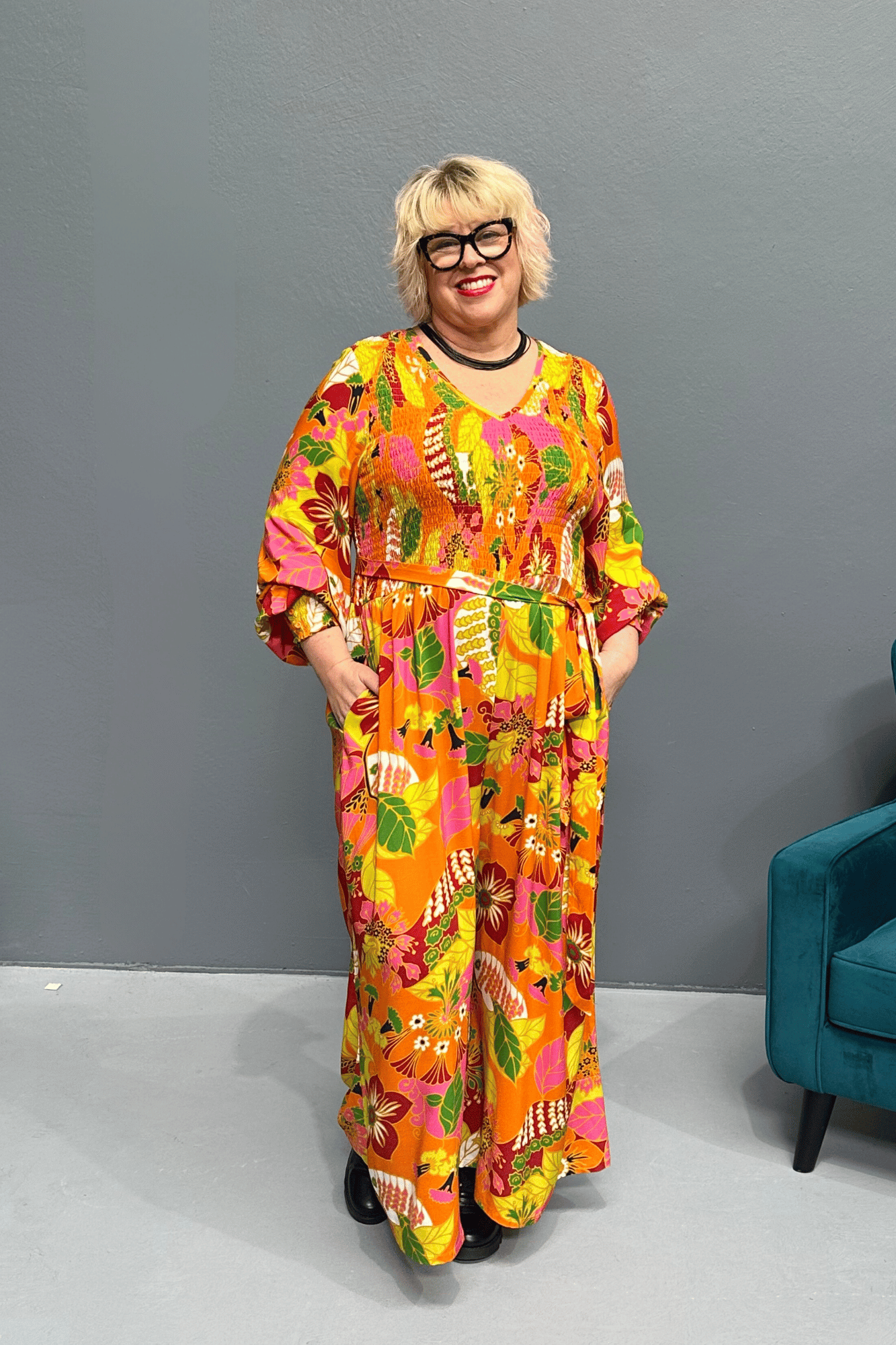 Plus-size 'FEARLESS' jumpsuit in retro print with pink, orange, and golden yellows, featuring a relaxed wide-leg cut and flattering shirred bodice.