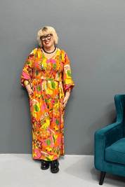 Plus-size 'FEARLESS' jumpsuit in retro print with pink, orange, and golden yellows, featuring a relaxed wide-leg cut and flattering shirred bodice.