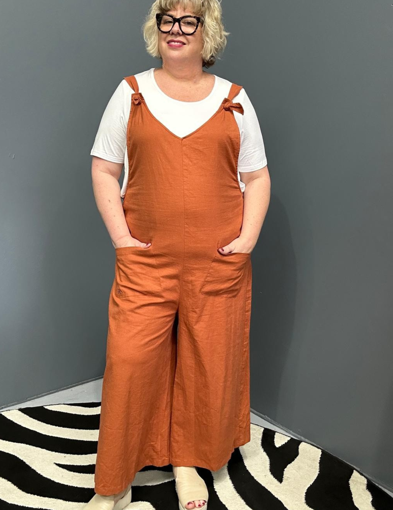 Front view of a plus-size woman wearing the 'BILLIE' stretch linen overalls in rust – relaxed fit with adjustable straps and a flattering design for curvy women