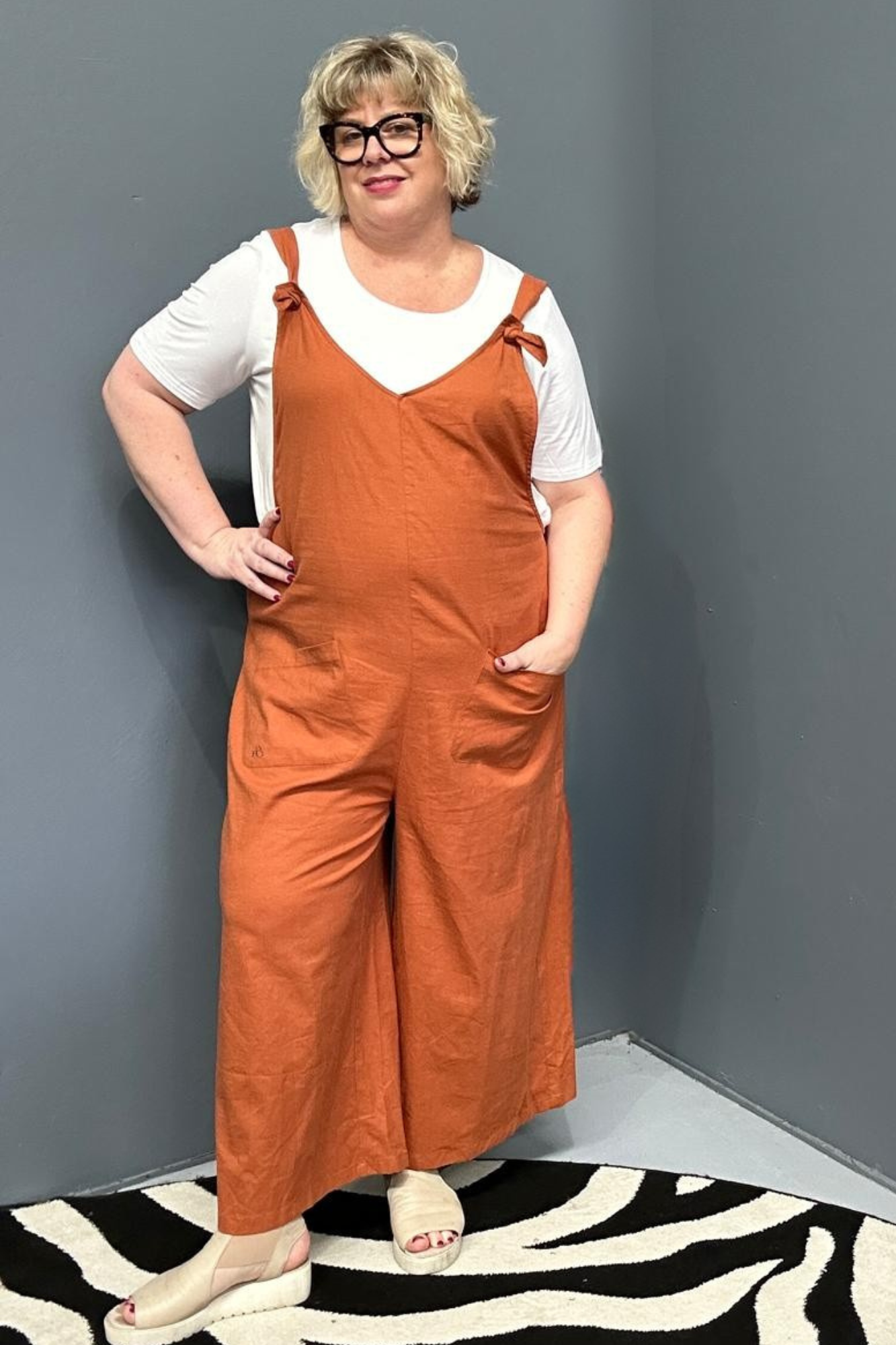 Front view of a plus-size woman wearing the 'BILLIE' stretch linen overalls in rust – relaxed fit with adjustable straps and a flattering design for curvy women
